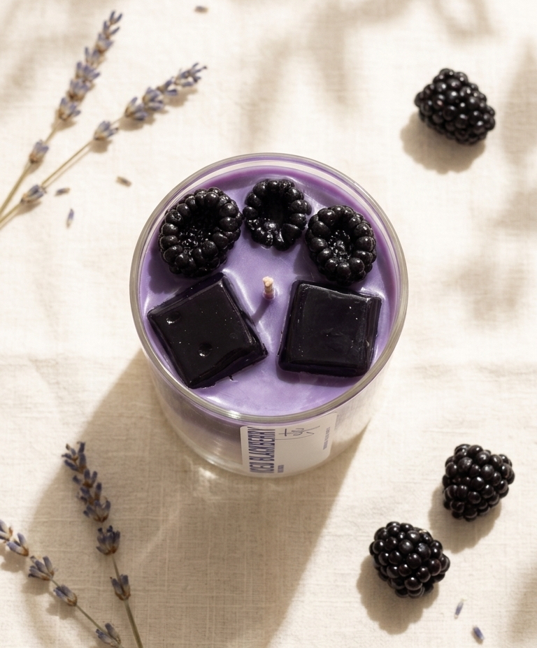 Purple candle with blackberries on a light fabric background